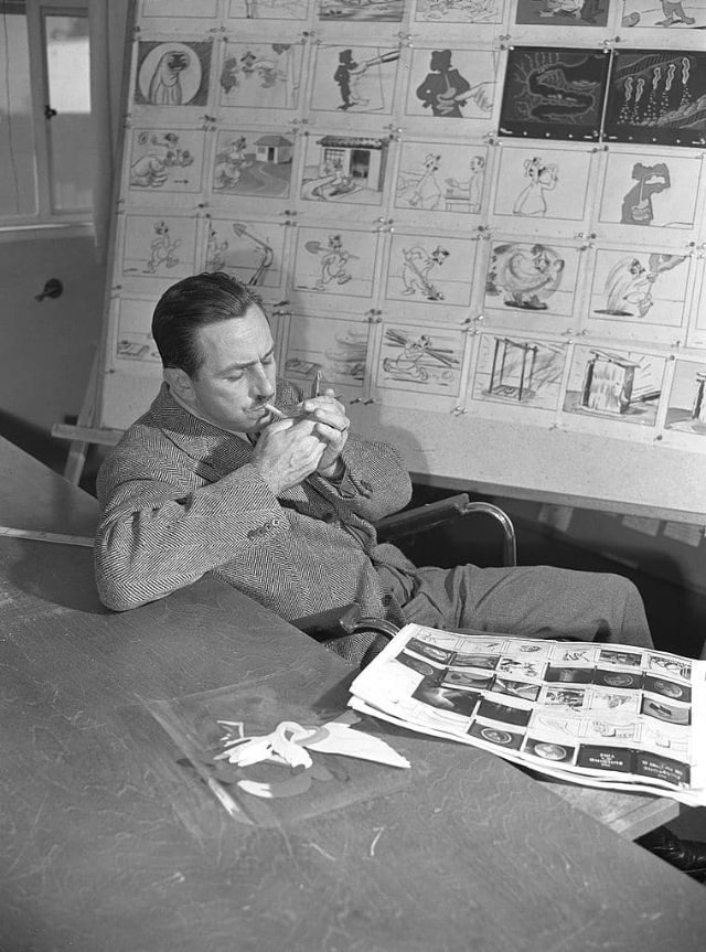 Acendendo um cigarro enquanto está sentado ao lado de um storyboard para o curta animado "Hookworm", Los Angeles, 1945. (Earl Theisen). Walt Disney era fumante compulsivo, hábito que o levou a morte em 1966 por câncer no pulmão.